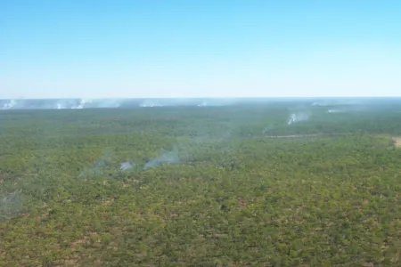 Aerial view of savannah bushland with smoke from small scattered fires